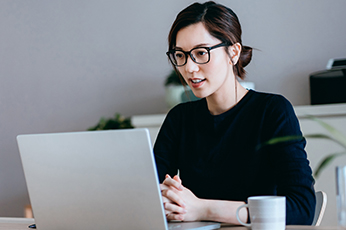 Woman in glasses participating in video call at home office with coffee mug