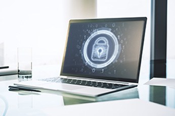 Laptop displaying glowing padlock icon on screen representing data security on glass desk