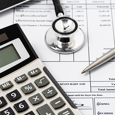 Stethoscope and calculator resting on a medical billing statement next to a pen