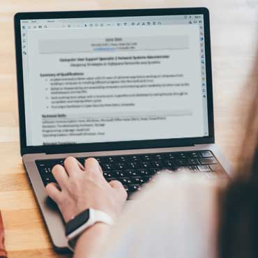 Woman exploring good skills to put on a resume while working on her laptop at a desk.