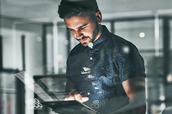 Man interacting with holographic touchscreen tablet, analyzing data overlays in modern office