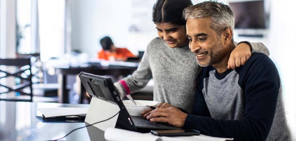 Dad and daughter collaborating on a tablet while doing homework at kitchen table