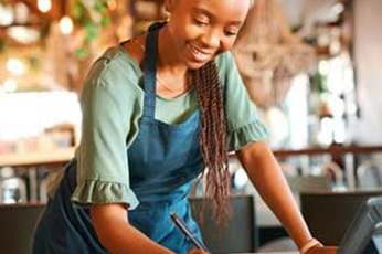 Small business owner smiling while organizing tasks after learning how to start a small business.